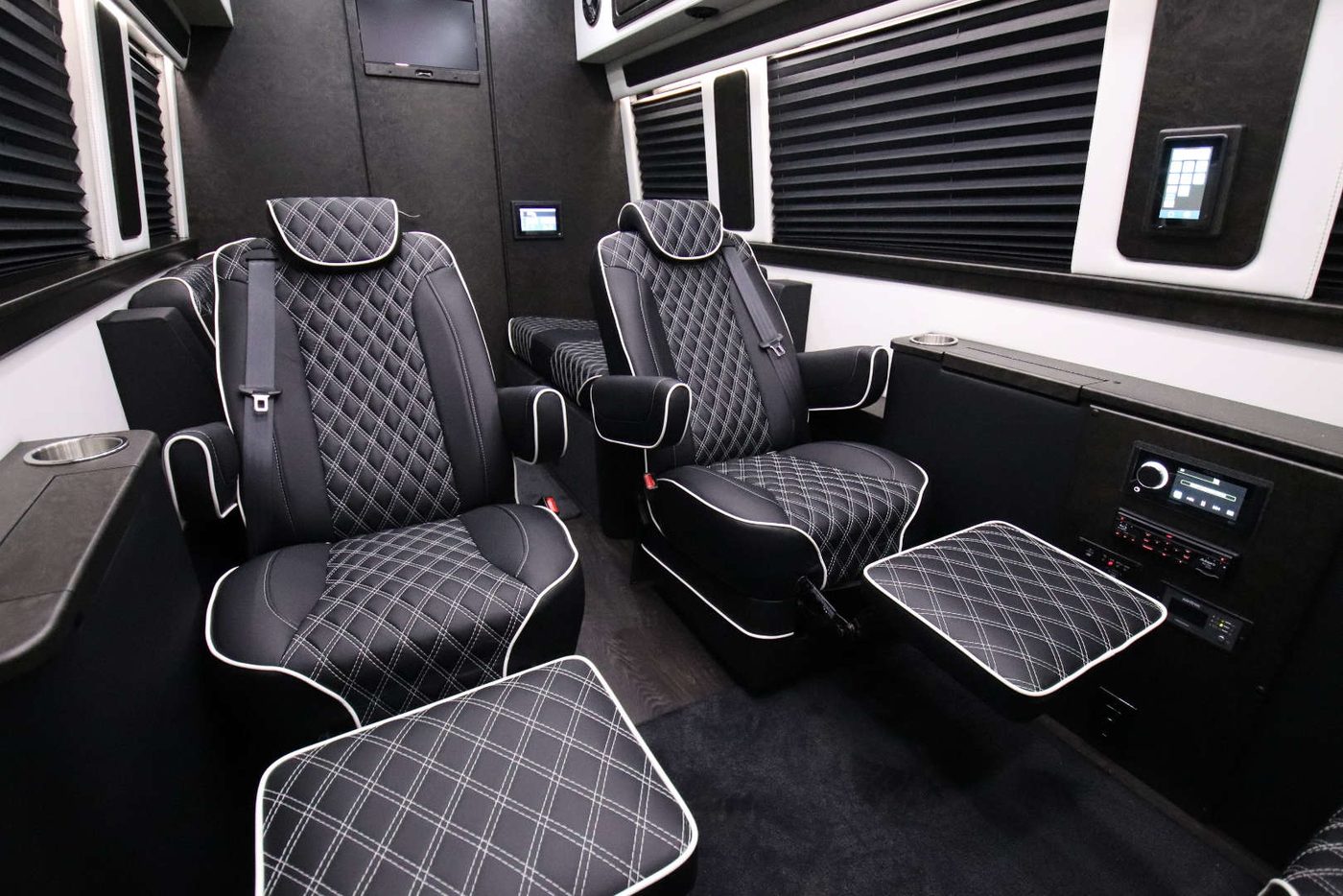 Four reclining diamond-stitched captain's chairs facing each other with a wood table and overhead television