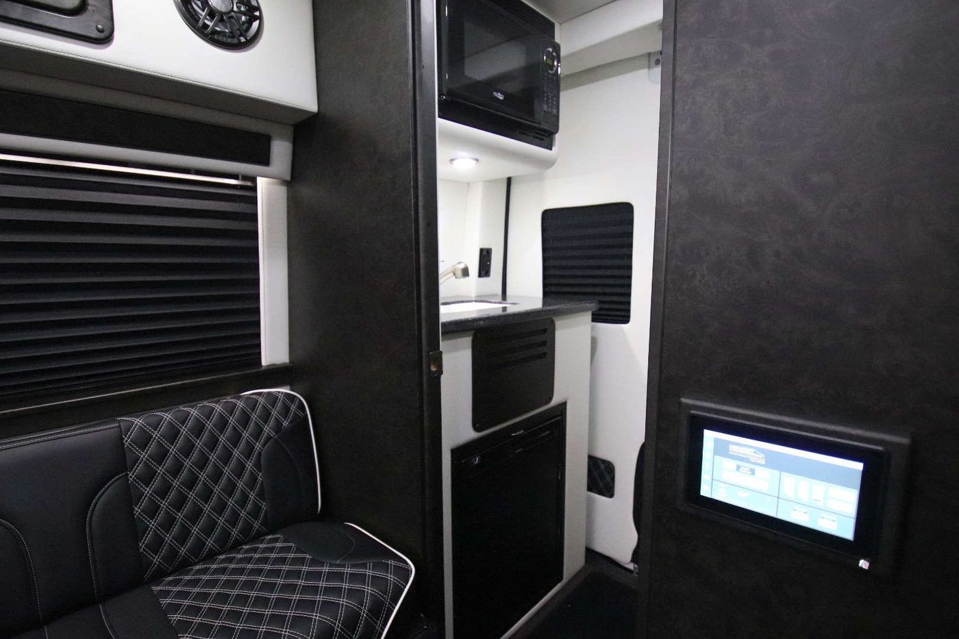 Onboard galley with sink, refrigerator, and microwave beside a leather bench seat