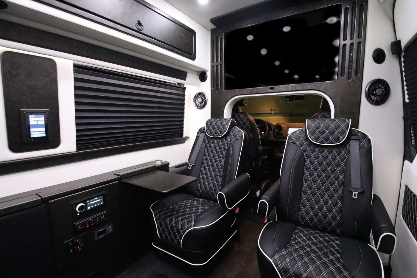 Sprinter coach cabin with a large flat-screen television mounted at the front bulkhead