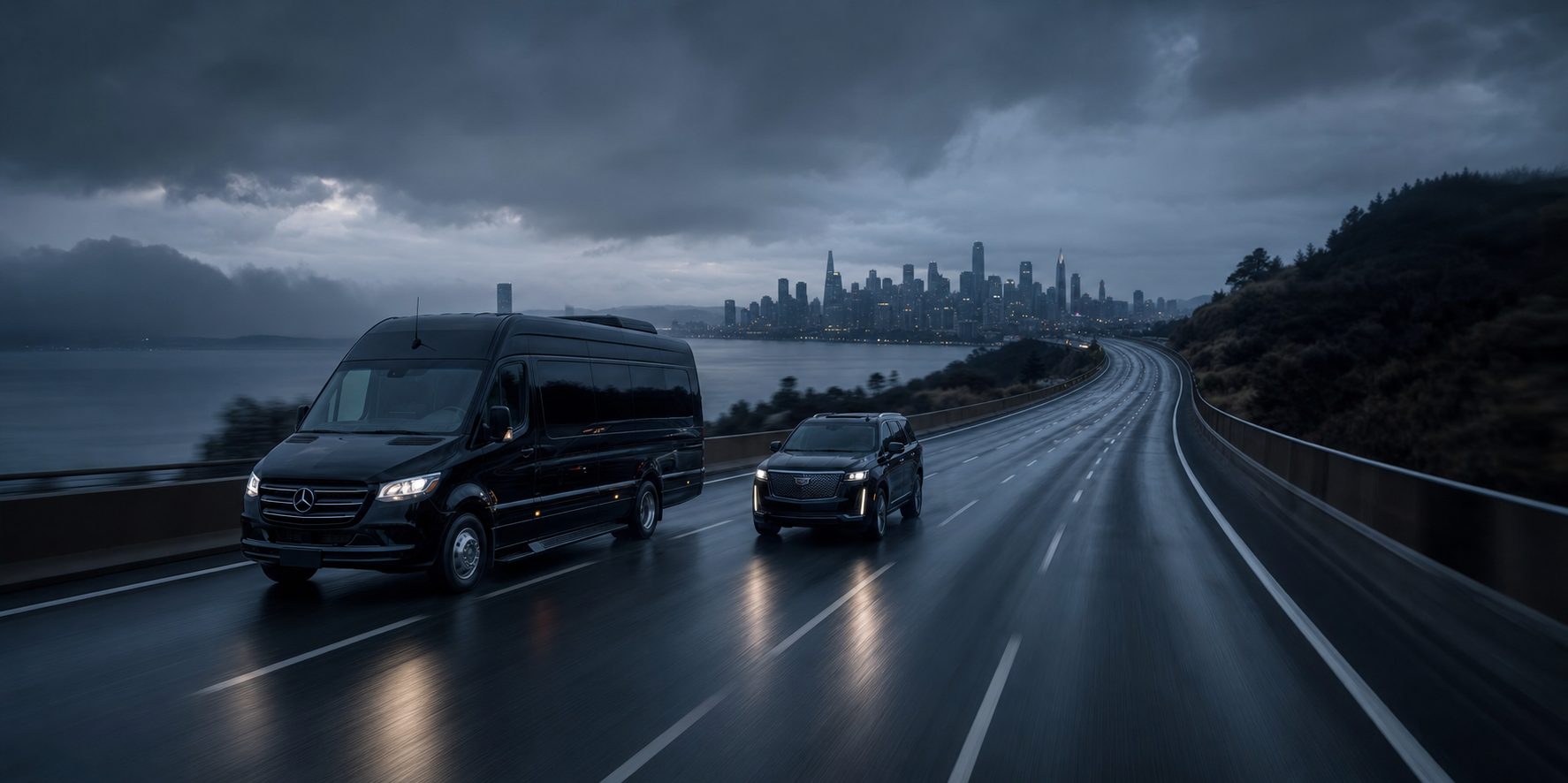 A Sprinter coach and executive SUV traveling in formation on a rain-slicked highway at dusk